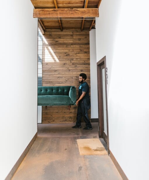 A man takes a sofa to a room