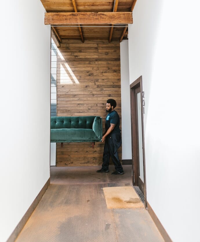 A man takes a sofa to a room