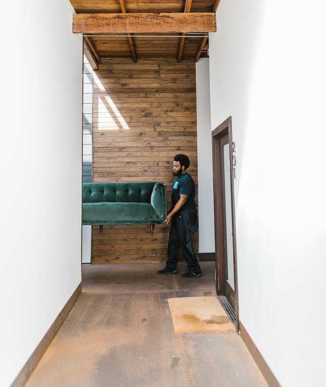 A man takes a sofa to a room